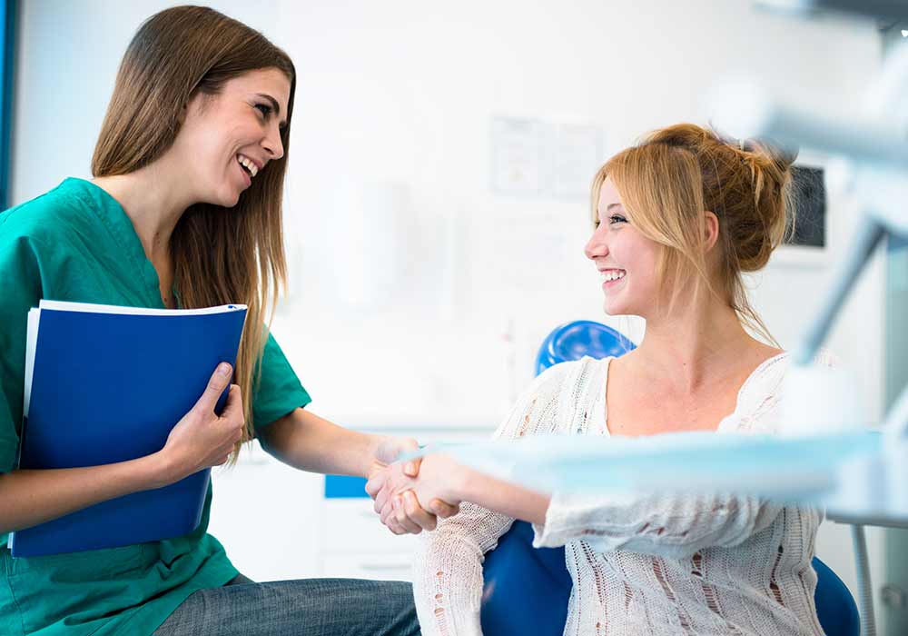 Female patient and female hygienist shaking hands